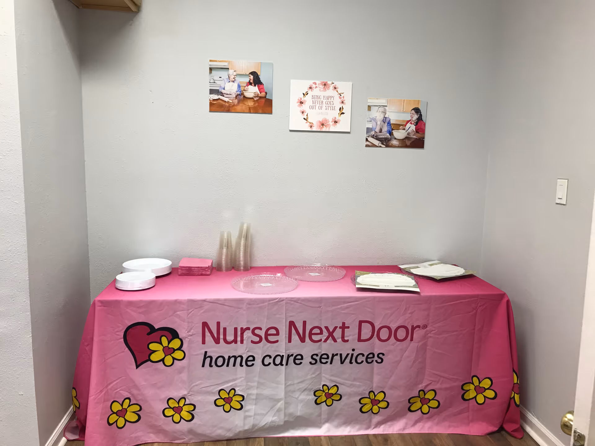 Pink Nurse Next Door table cover on a table against a gray wall with photos.
