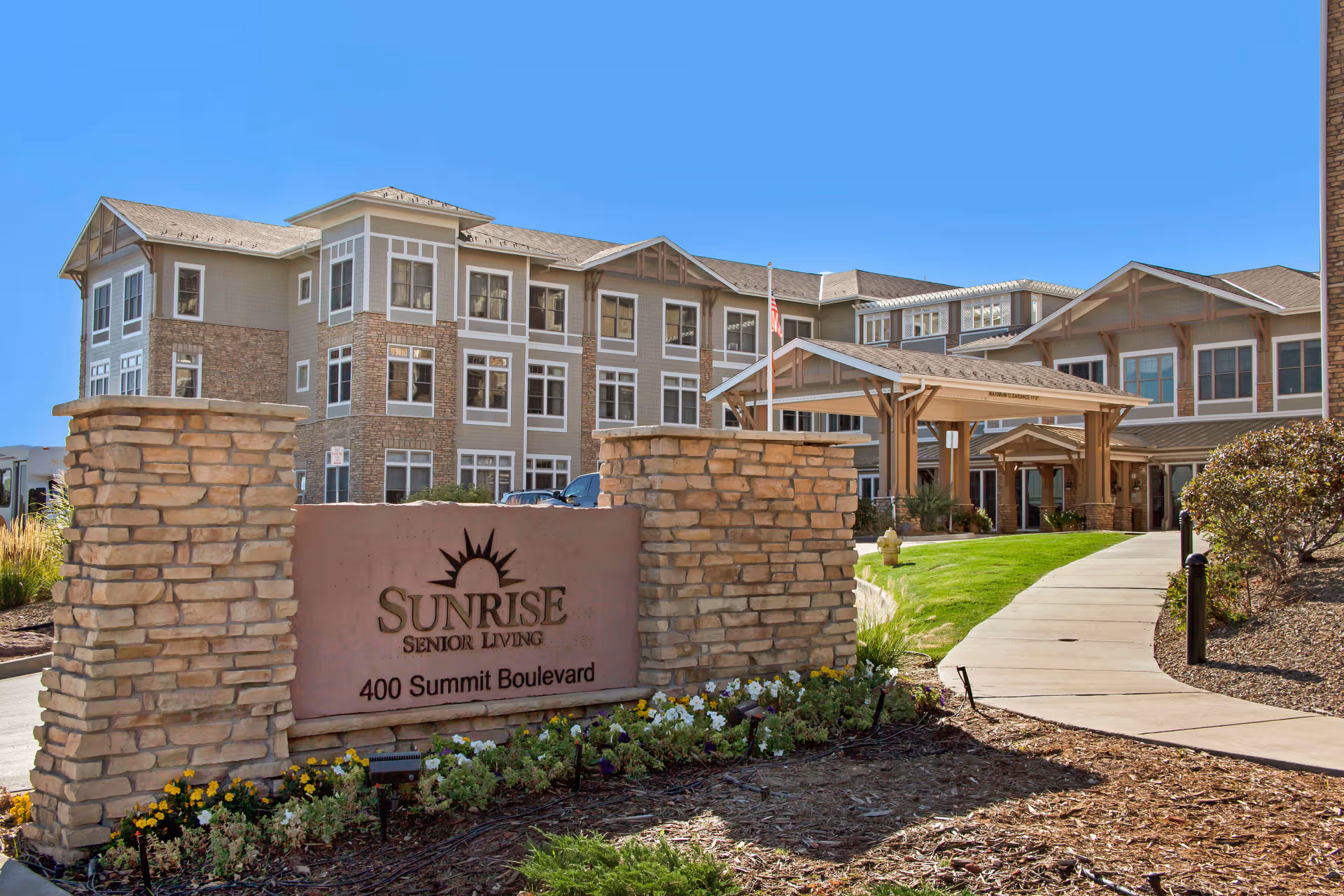 Sunrise Senior Living facility front entrance with stone sign and landscaped walkway.