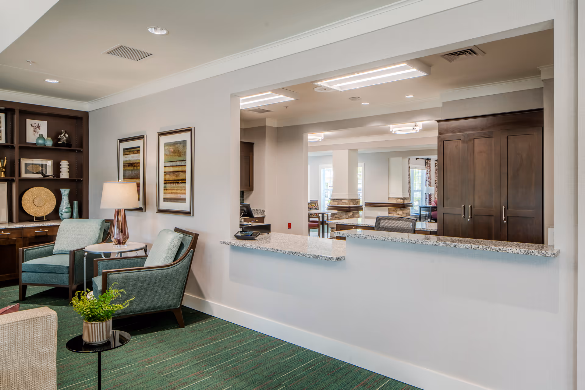Bright senior living lobby with seating, a reception counter, and decorative shelves