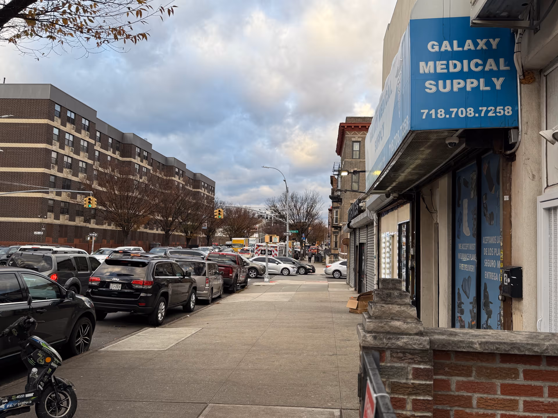 Street view with parked cars and Galaxy Medical Supply storefront on a cloudy day
