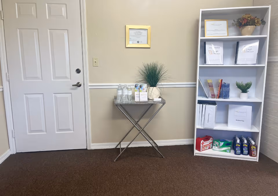 Interior hallway featuring a door left, a metal folding table, bottles, and a white bookshelf.