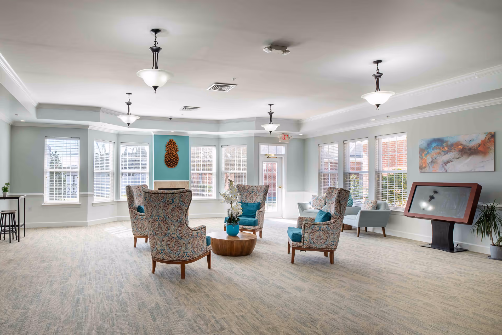Bright lounge with patterned chairs around a circular wood coffee table in a spacious common area.