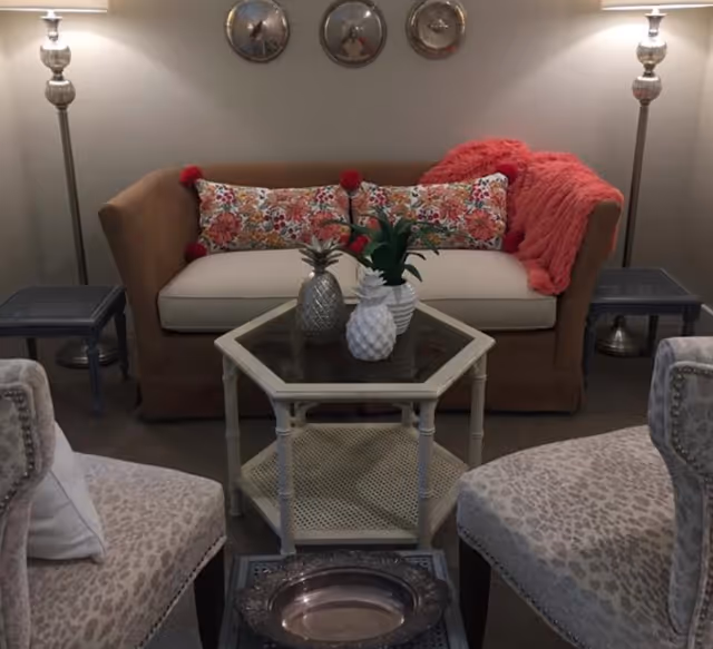 Cozy living room area with brown sofa, floral pillows, and glass coffee table.