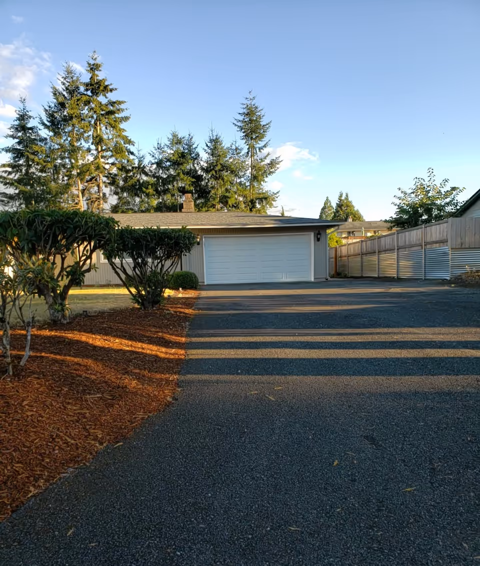 Exterior view of a single-story senior living facility with a two-car garage and trees.