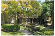 Exterior view of Heritage Park at Alta Loma; trees, shrubs, and a walkway to the entrance.