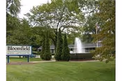 Exterior view of Bloomfield Health Care Center with sign, fountain, and surrounding lawn.