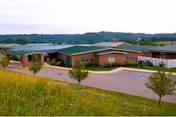 Exterior view of Kimes Nursing and Rehab Center building with green roof and parking.