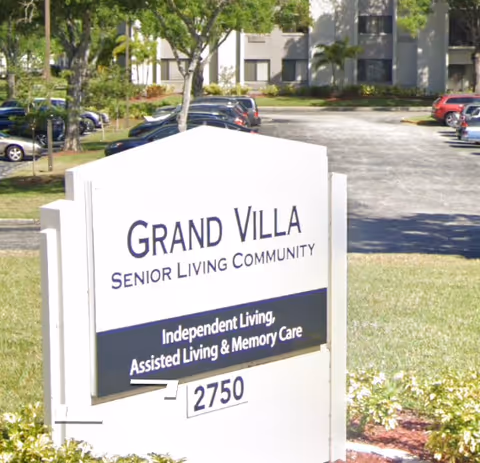 White Grand Villa sign reading Senior Living Community sits in front of a building.