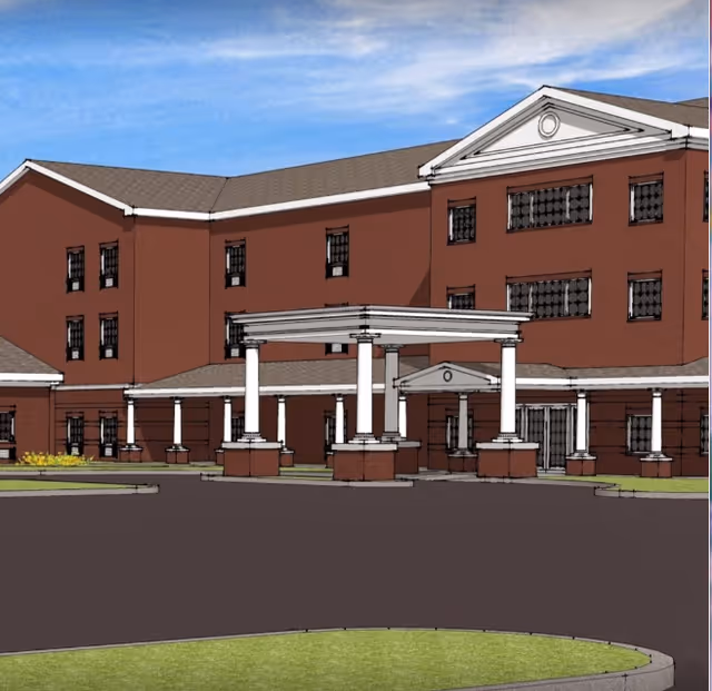 Red-brick Crimson Village senior living building with white columns and a circular driveway at the entrance.