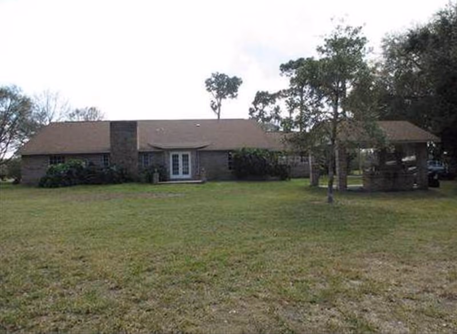 Single story senior living building with front entrance, lawn, and a covered carport on the right.