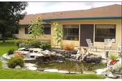 Exterior of a senior living facility with a stone water feature and patio seating.