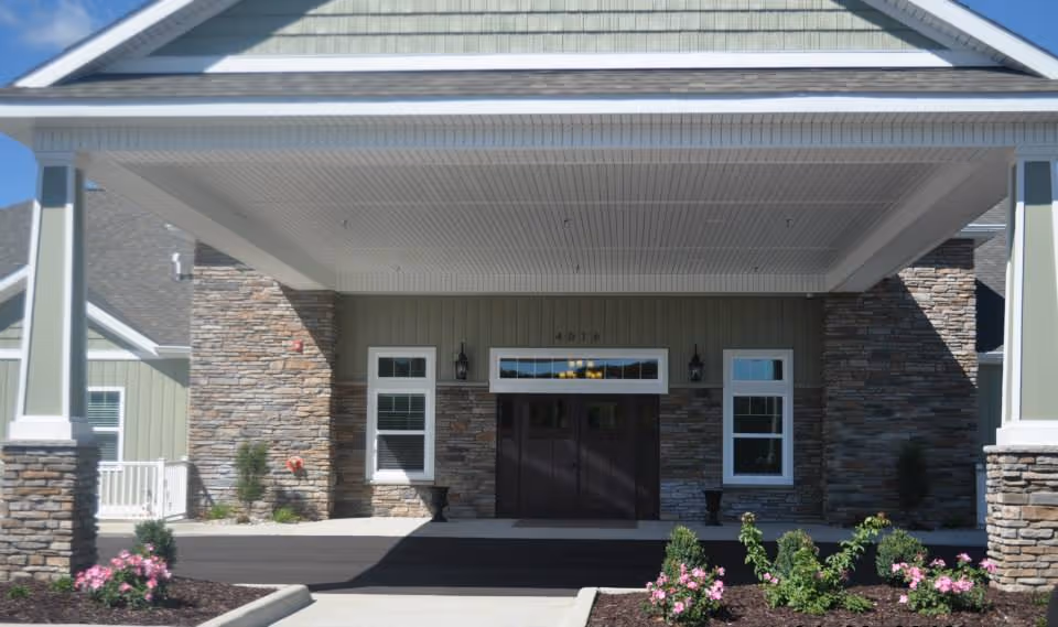Front entrance of a luxury senior living facility with stone facade and covered porch.
