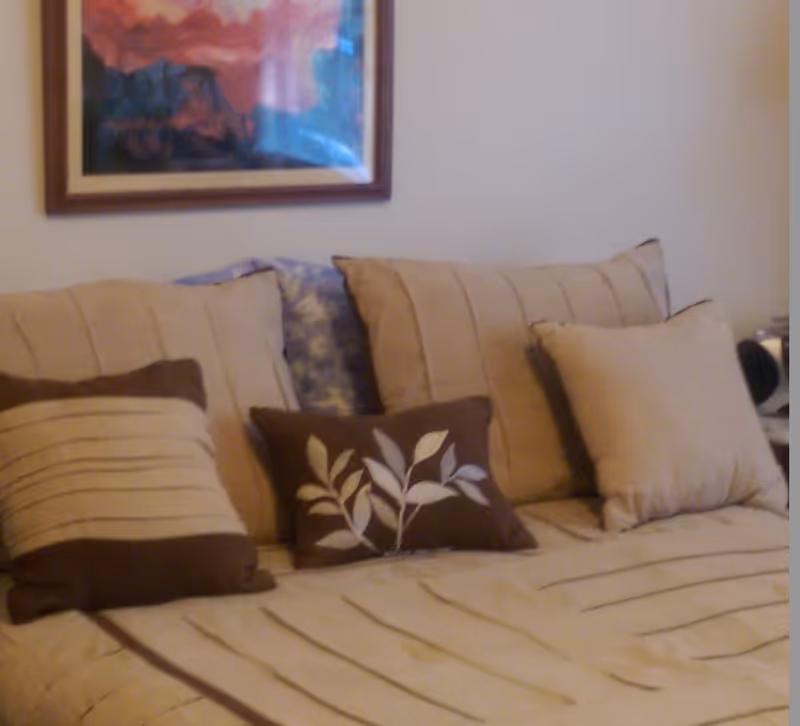 Beige sofa with striped pillows in a living room, framed artwork overhead.