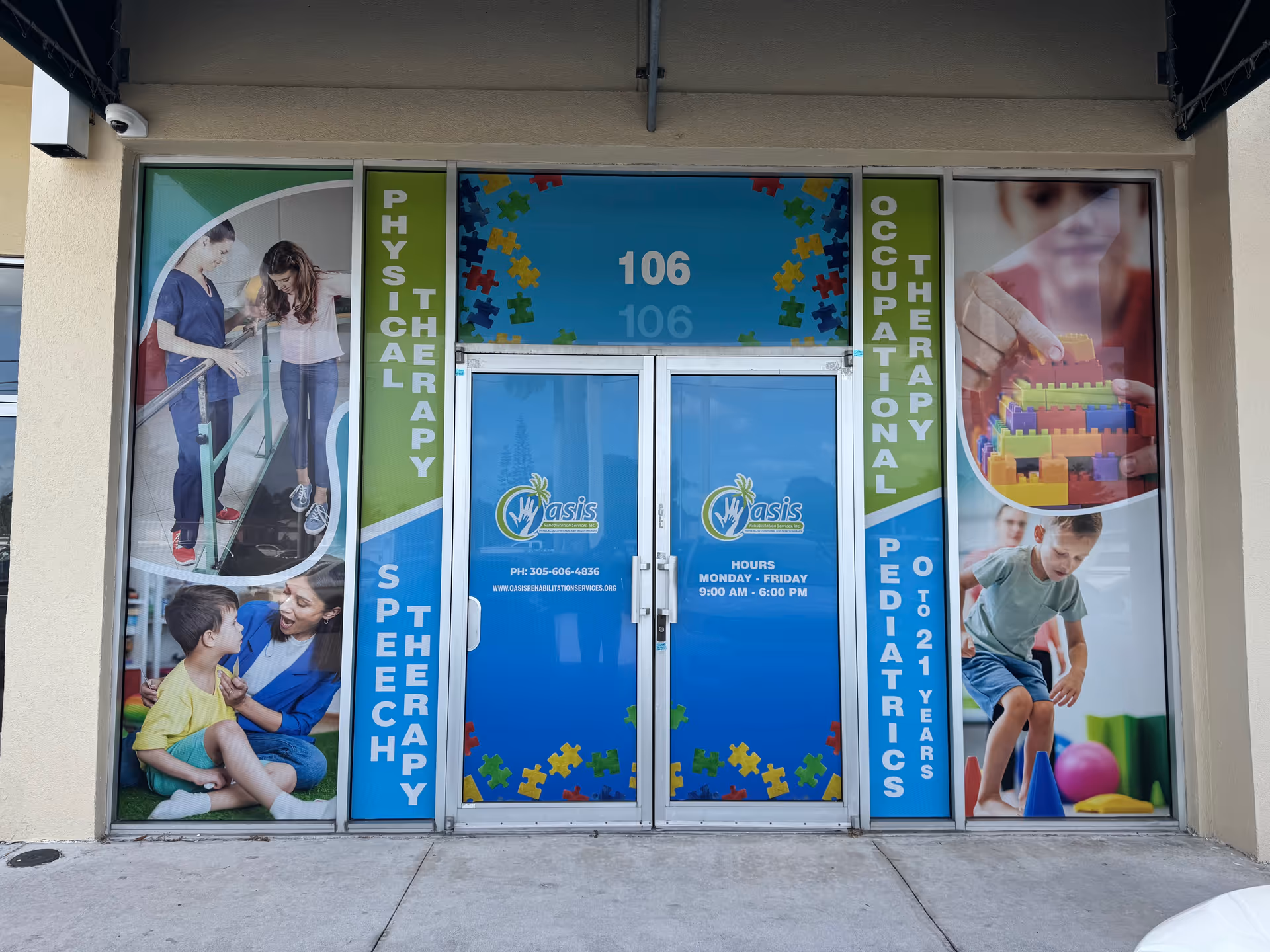 Front entrance of Oasis Rehabilitation Services with blue doors and bright banners.
