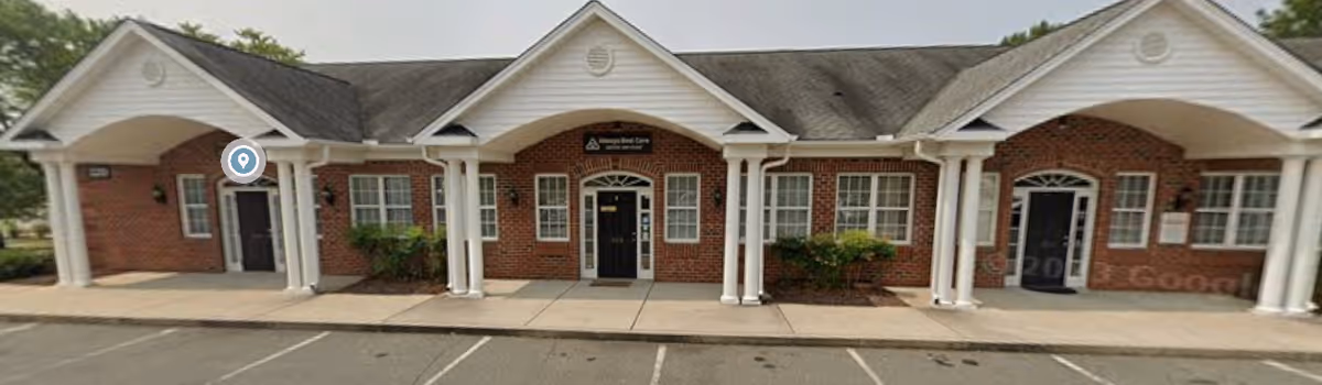 Brick building front of a senior care facility with arched entrances and white columns.