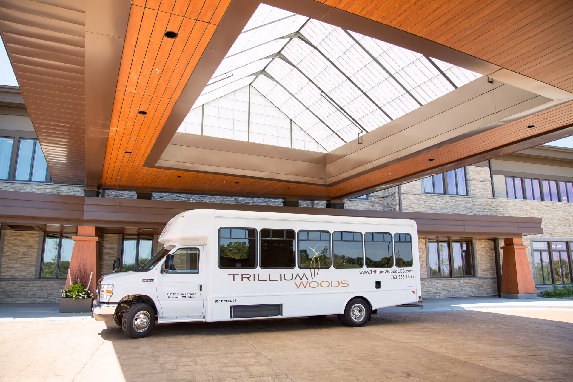White Trillium Woods shuttle bus parked in front of a modern facility entrance.
