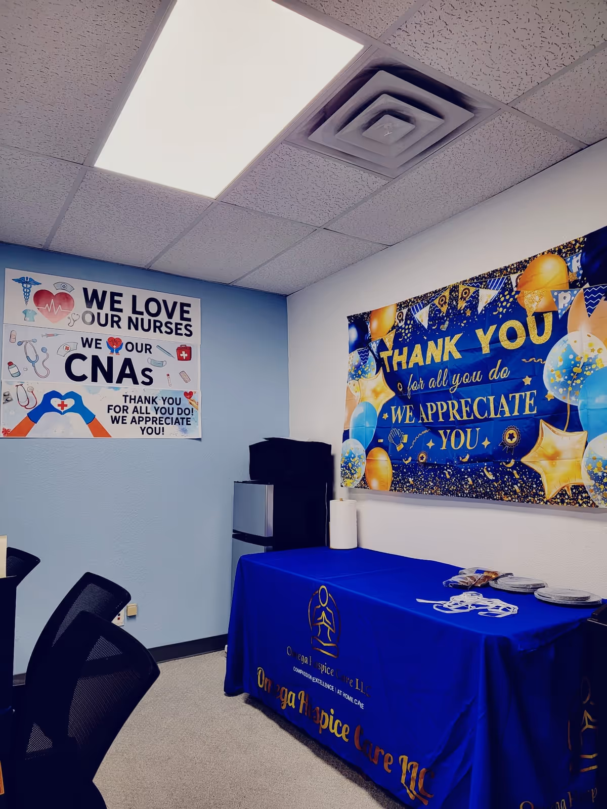Indoor room with nurses appreciation banners and a blue-draped table for Omega Hospice Care LLC.