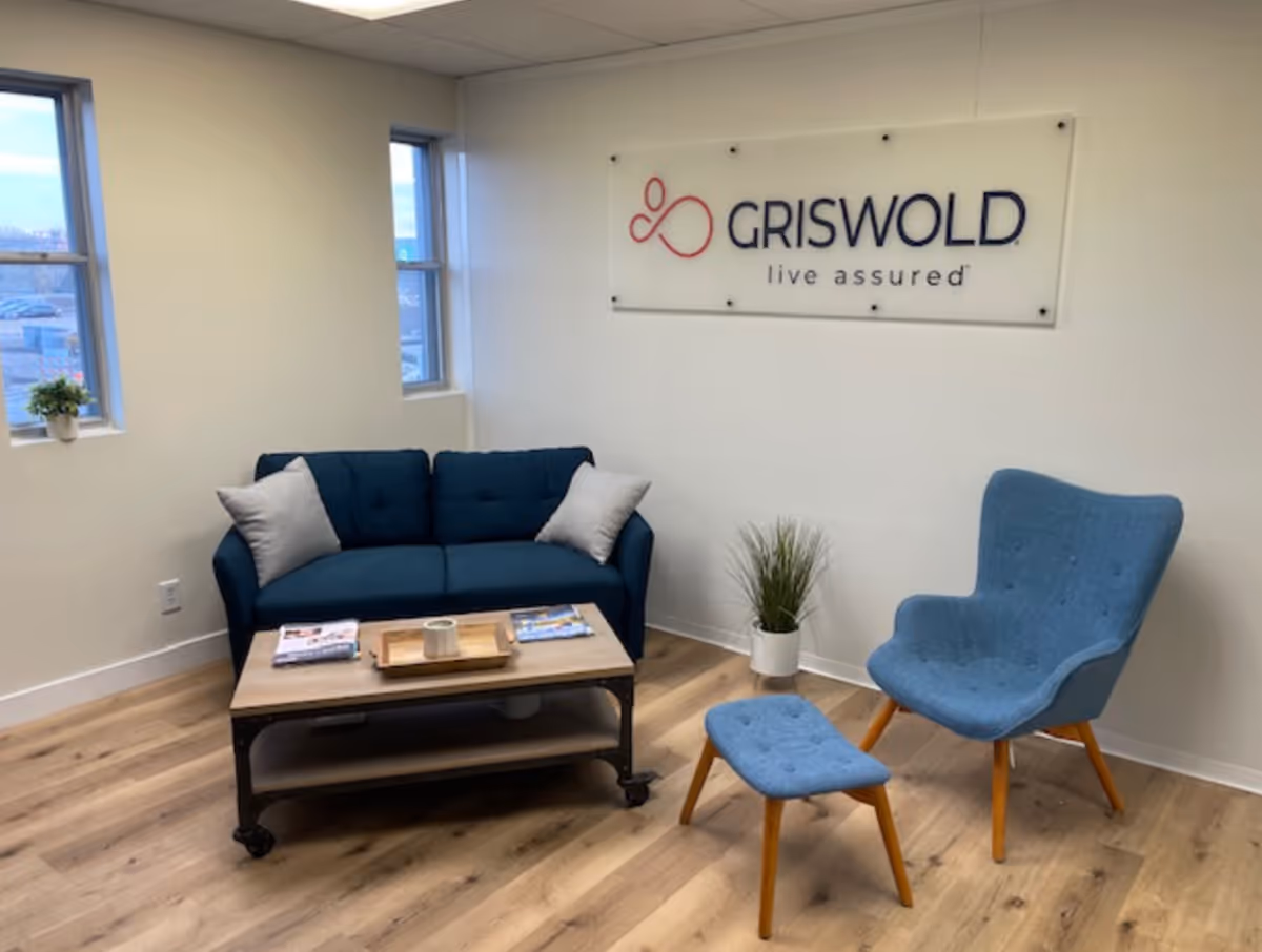 A modern senior living lounge with blue seating, a coffee table, and Griswold sign.