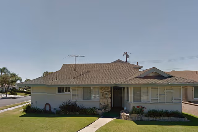 Single-story residential-style senior living facility exterior with front lawn and stone entry.