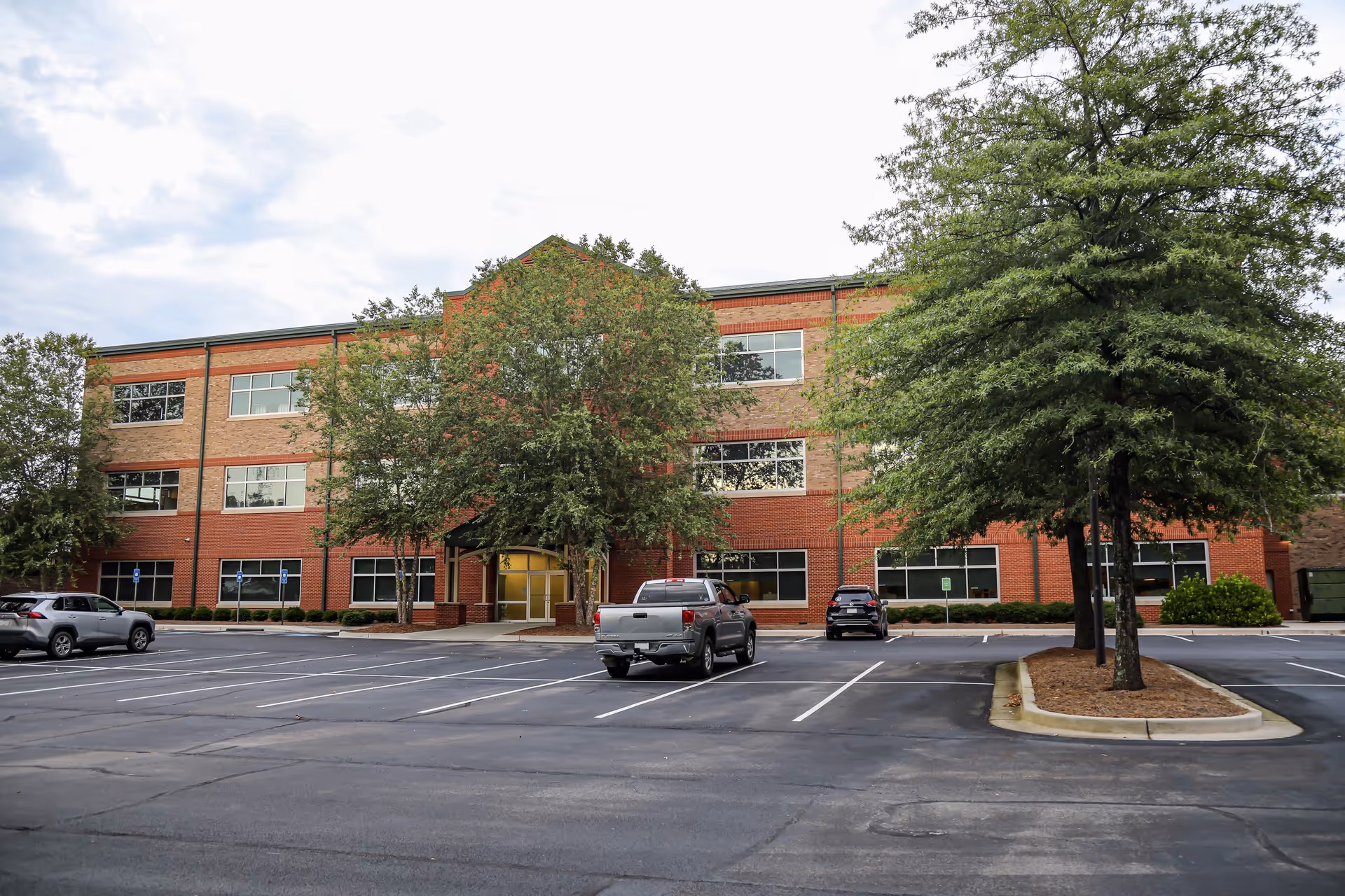 Exterior view of Tanner Hospice Care building with parked cars and trees in front.