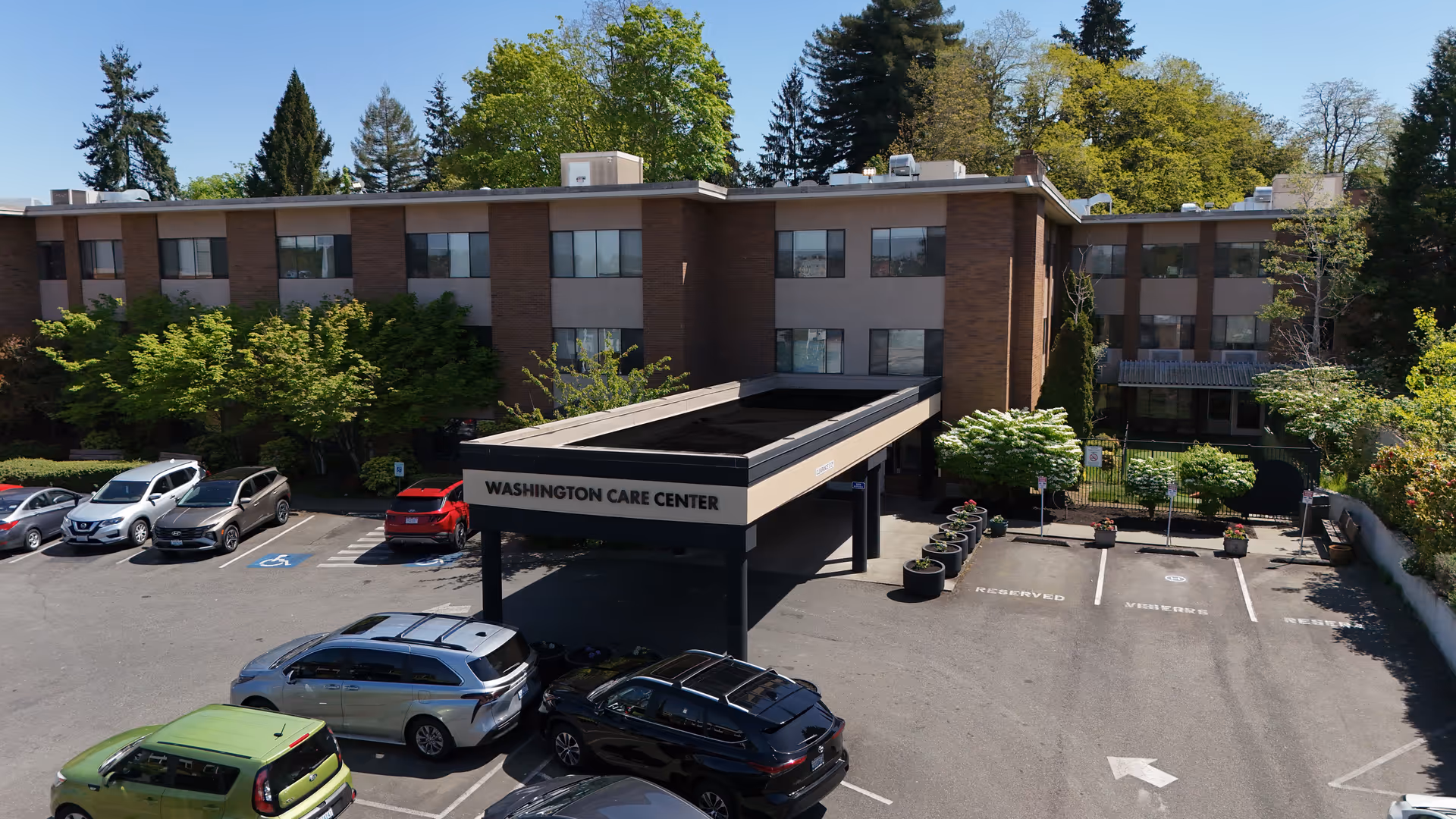 A senior care center building with a porte-cochere entrance and parked cars