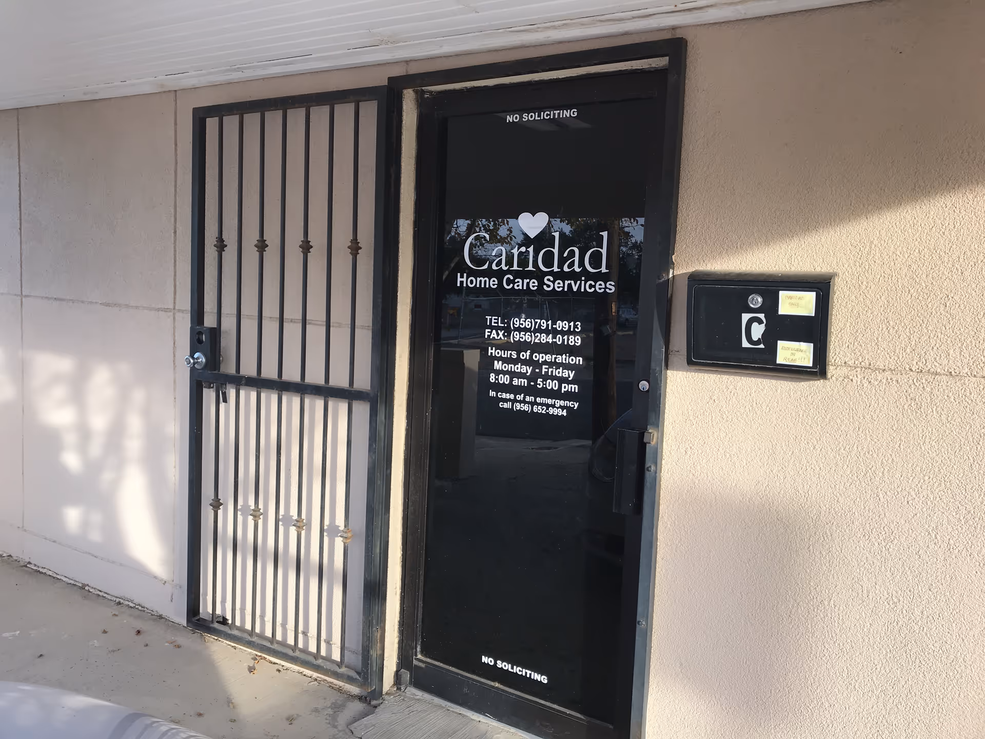 Exterior entrance to Caridad Home Care Services with a metal security gate.