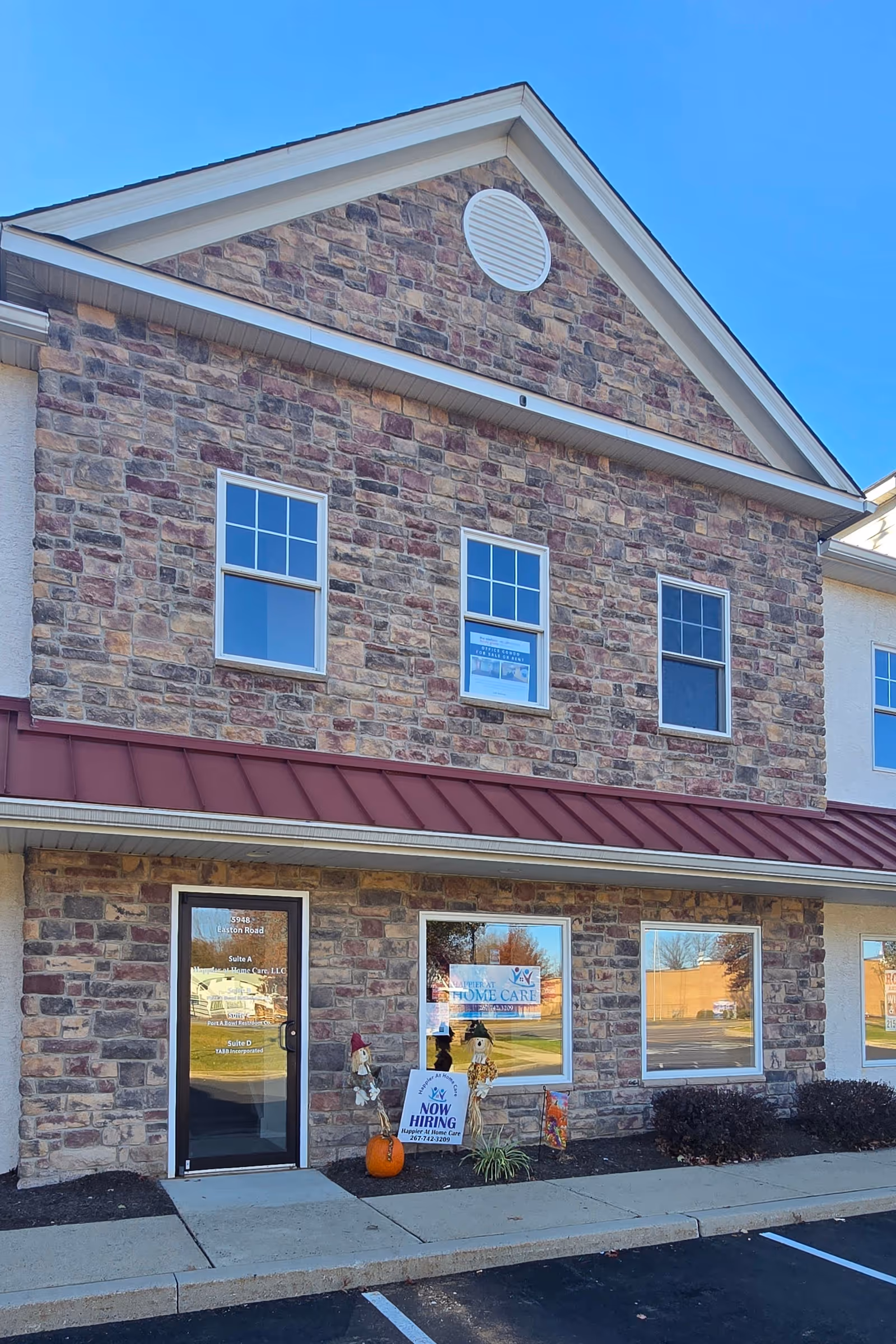 Front exterior of Happier At Home Care, LLC building with windows, signage, and pumpkin decor.