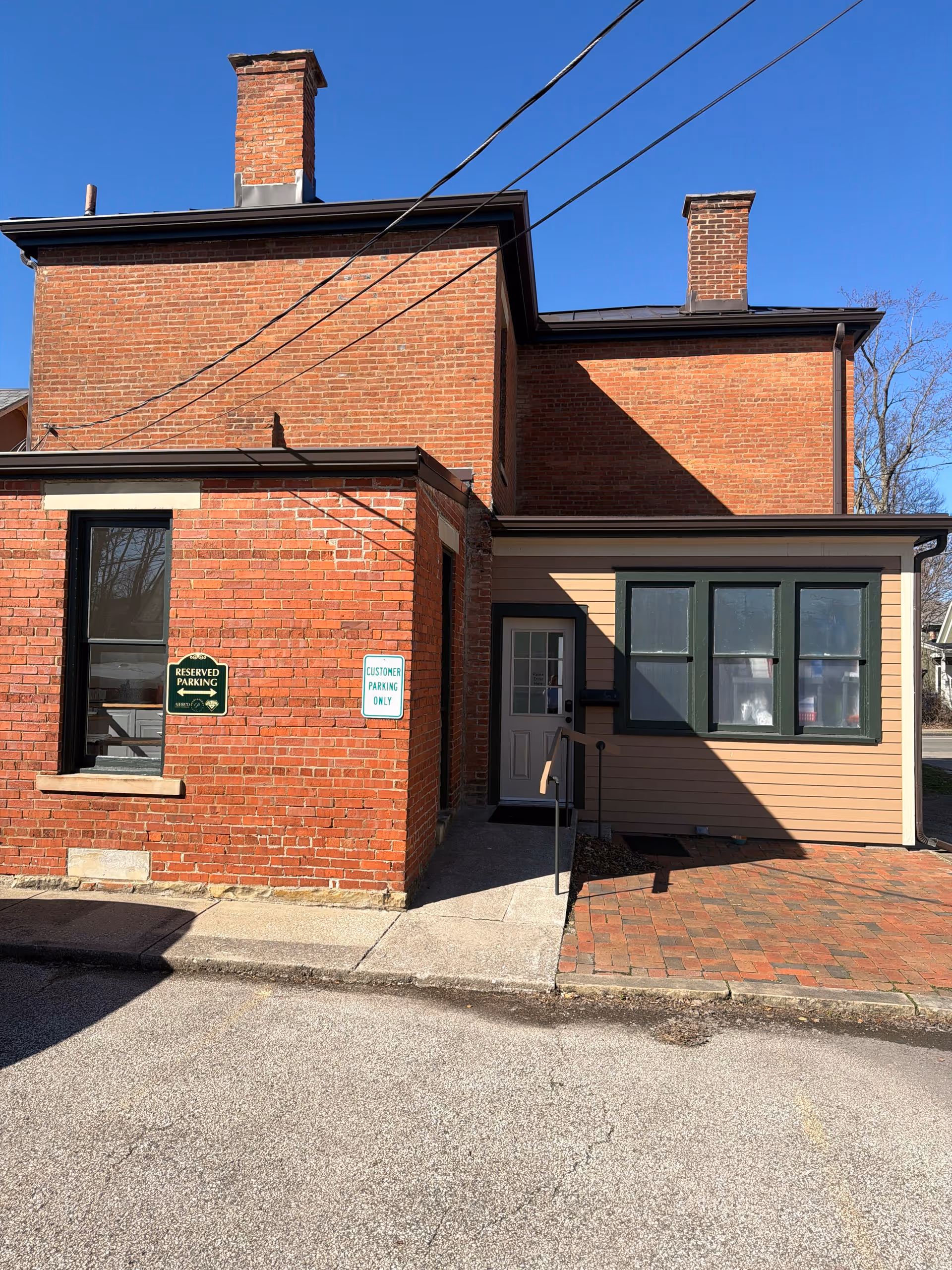 Brick building front with doorway, windows, and parking signs near entrance