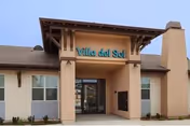 Exterior view of Villa del Sol senior living entrance under a wooden awning.
