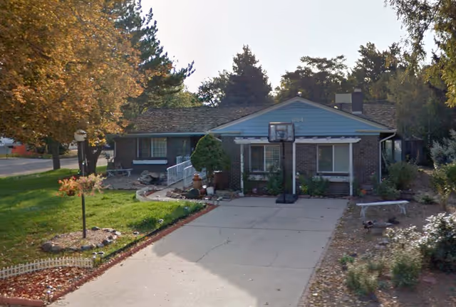 Front exterior of a single-story brick building with driveway, basketball hoop, and landscaping.