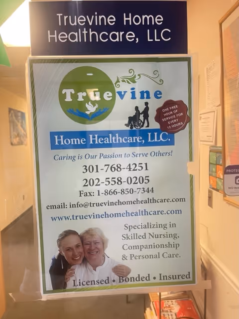 Indoor hallway sign for Truevine Home Healthcare, LLC, featuring logo, contact info, and photo.