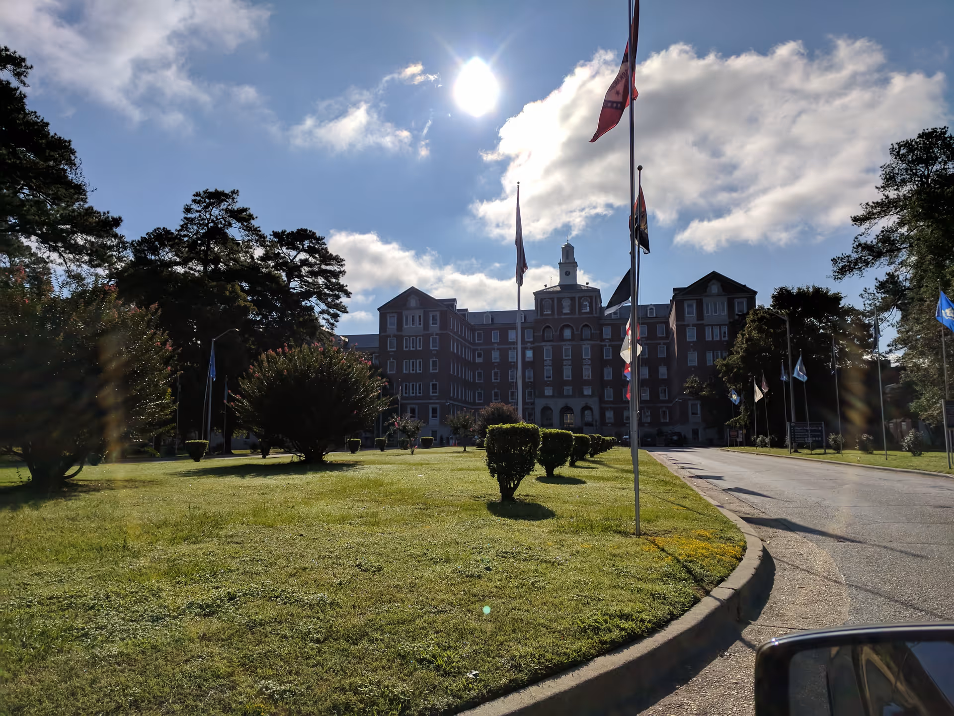 Front view of Fayetteville VA Medical Center with flagpoles, lawn, and blue sky.
