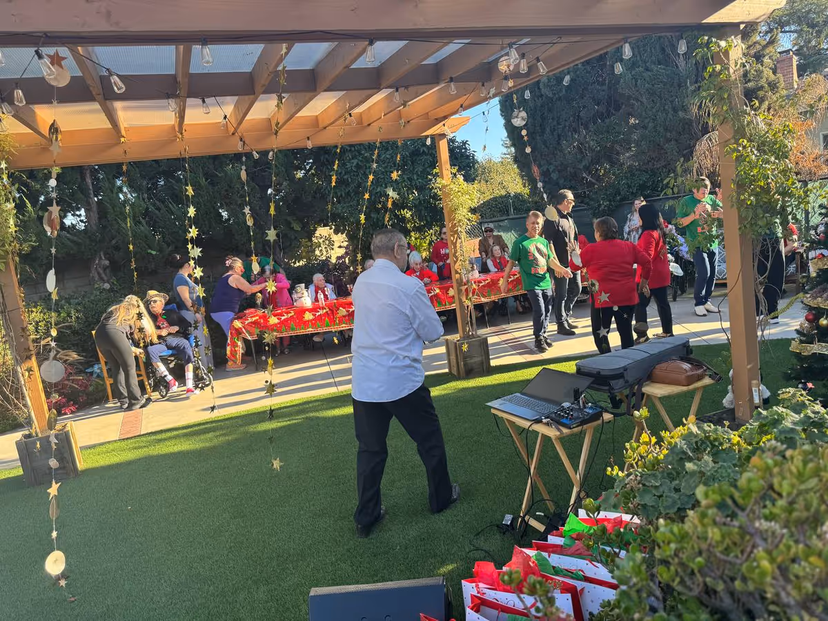 Outdoor courtyard event with residents and staff socializing under string lights.
