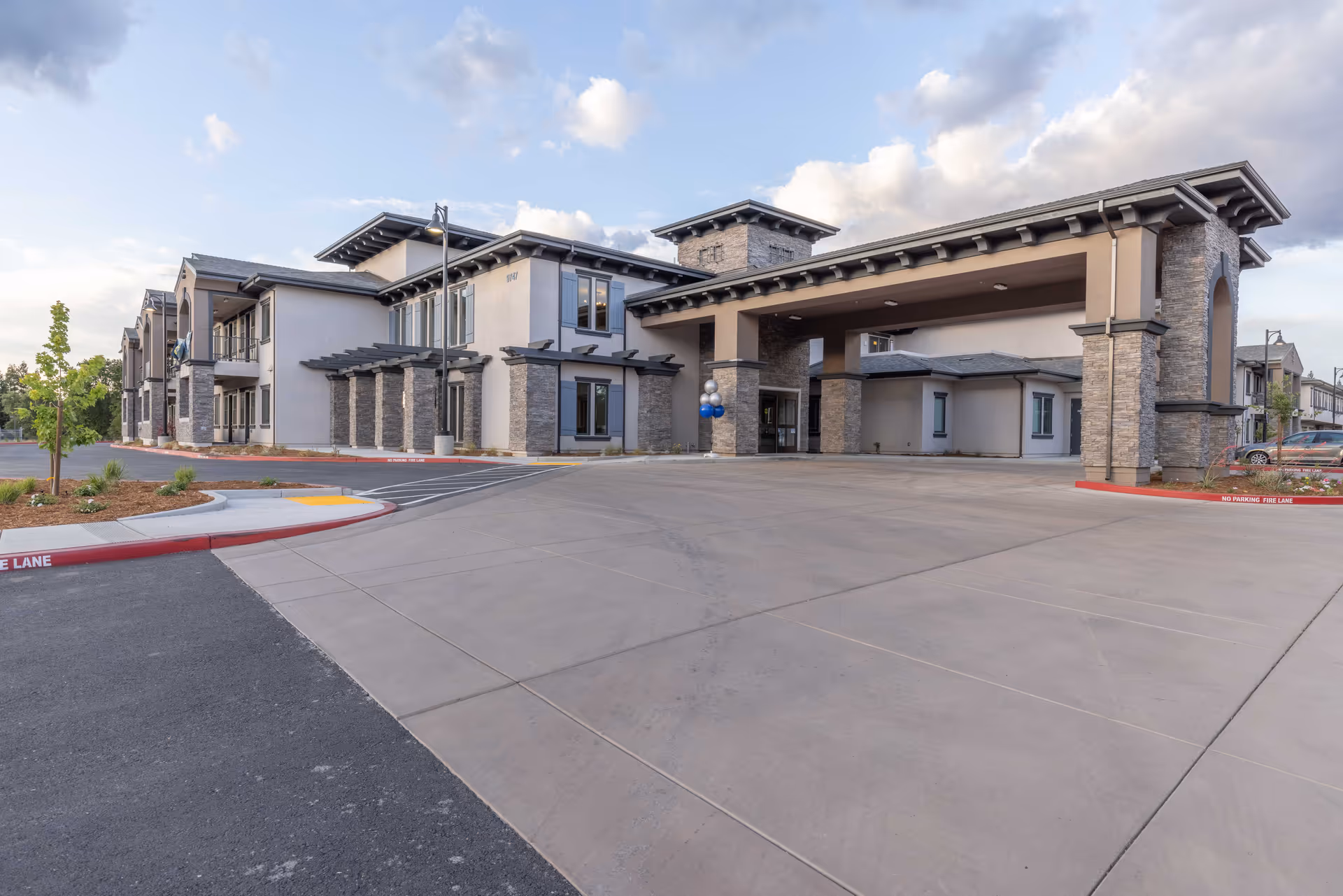 Exterior view of WellQuest of Granite Bay, showing a modern two-story building with stone and stucco facade, large covered entrance, and a spacious driveway under a partly cloudy sky.