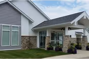 Exterior of a senior living facility with a covered entrance and stone pillars.