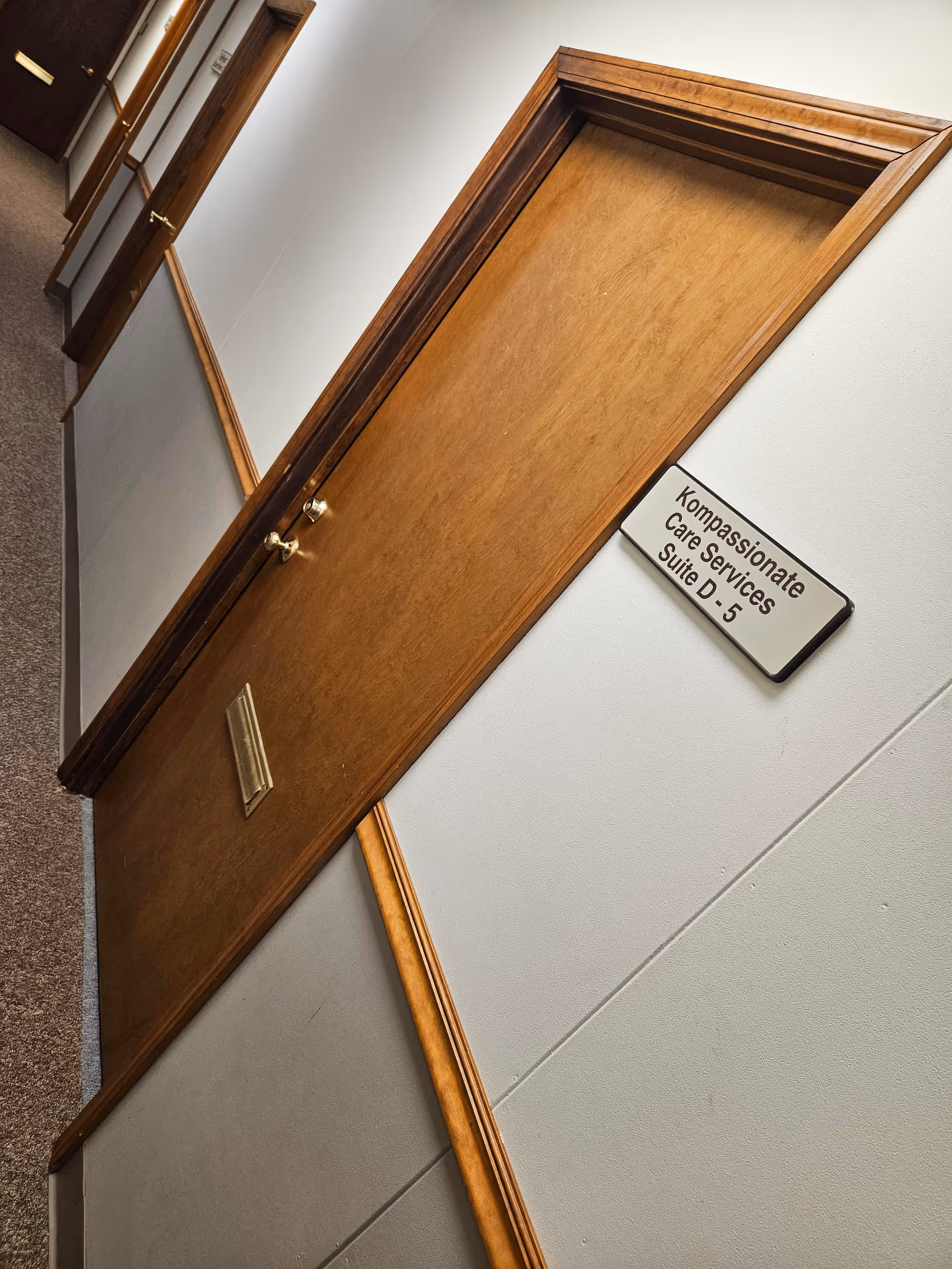 Interior hallway in a senior facility with wooden doors and a Suite D-5 sign.