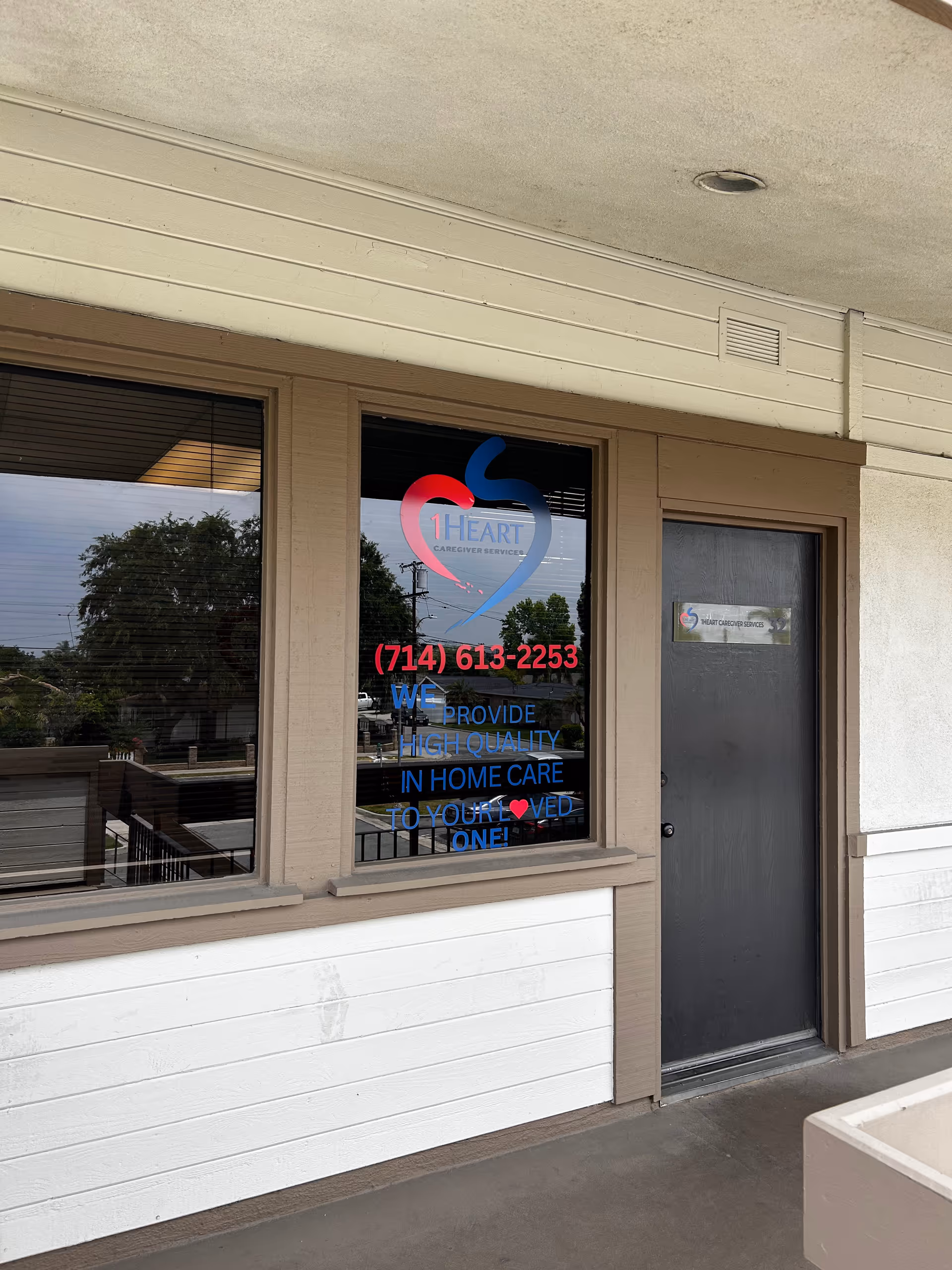 Exterior view of 1Heart Caregiver Services storefront with logo sign and door.