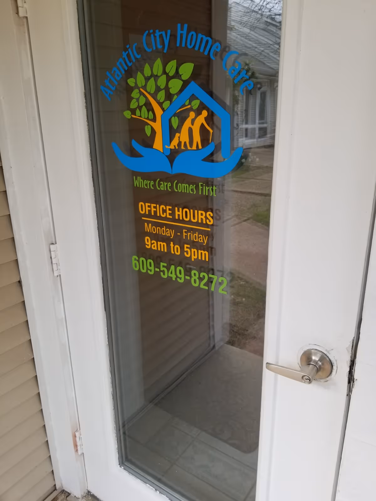 Front door of Atlantic City Home Care, LLC with colorful logo and hours on glass.