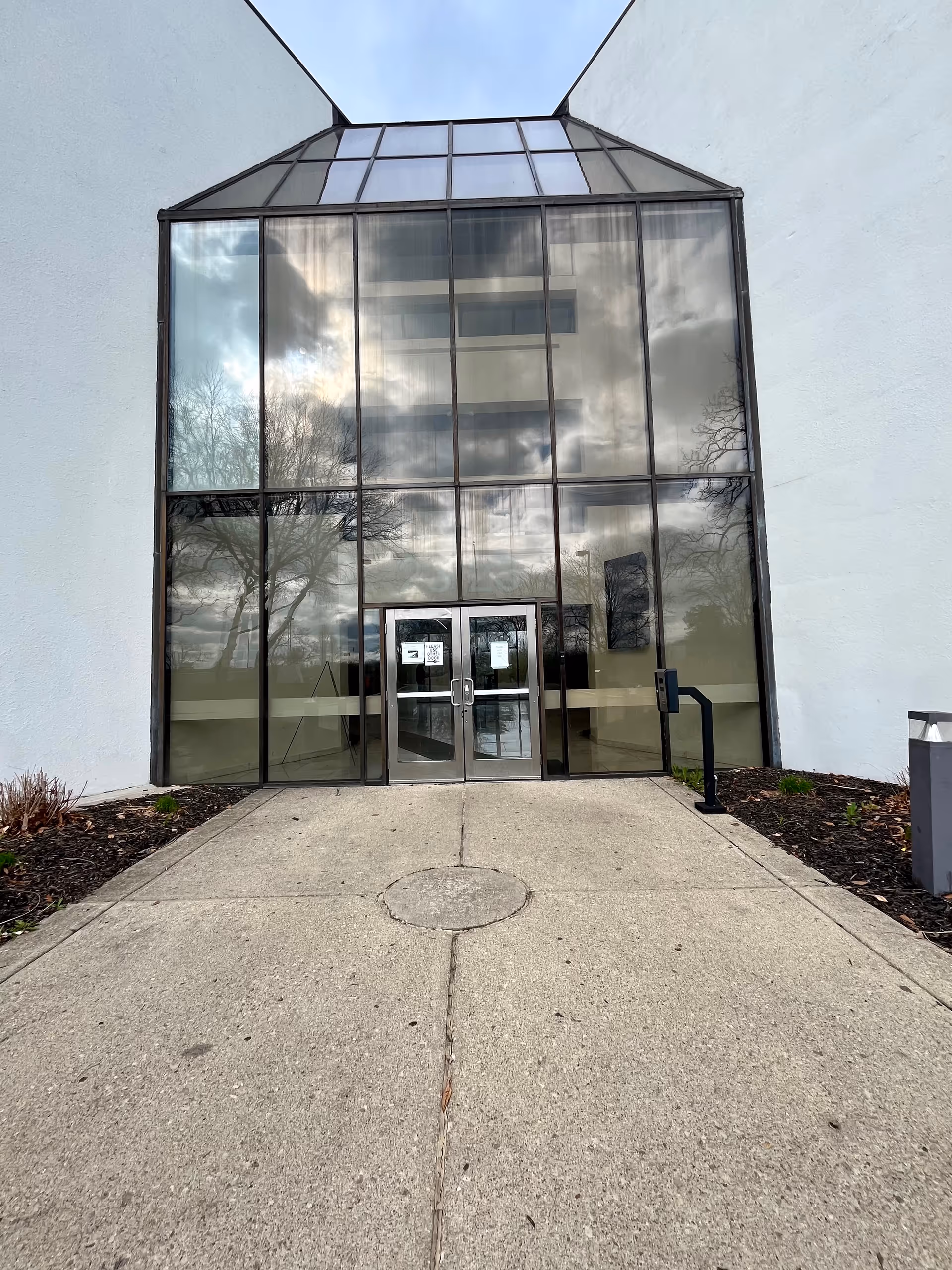 Glass-front entrance with large windows and a concrete walkway.