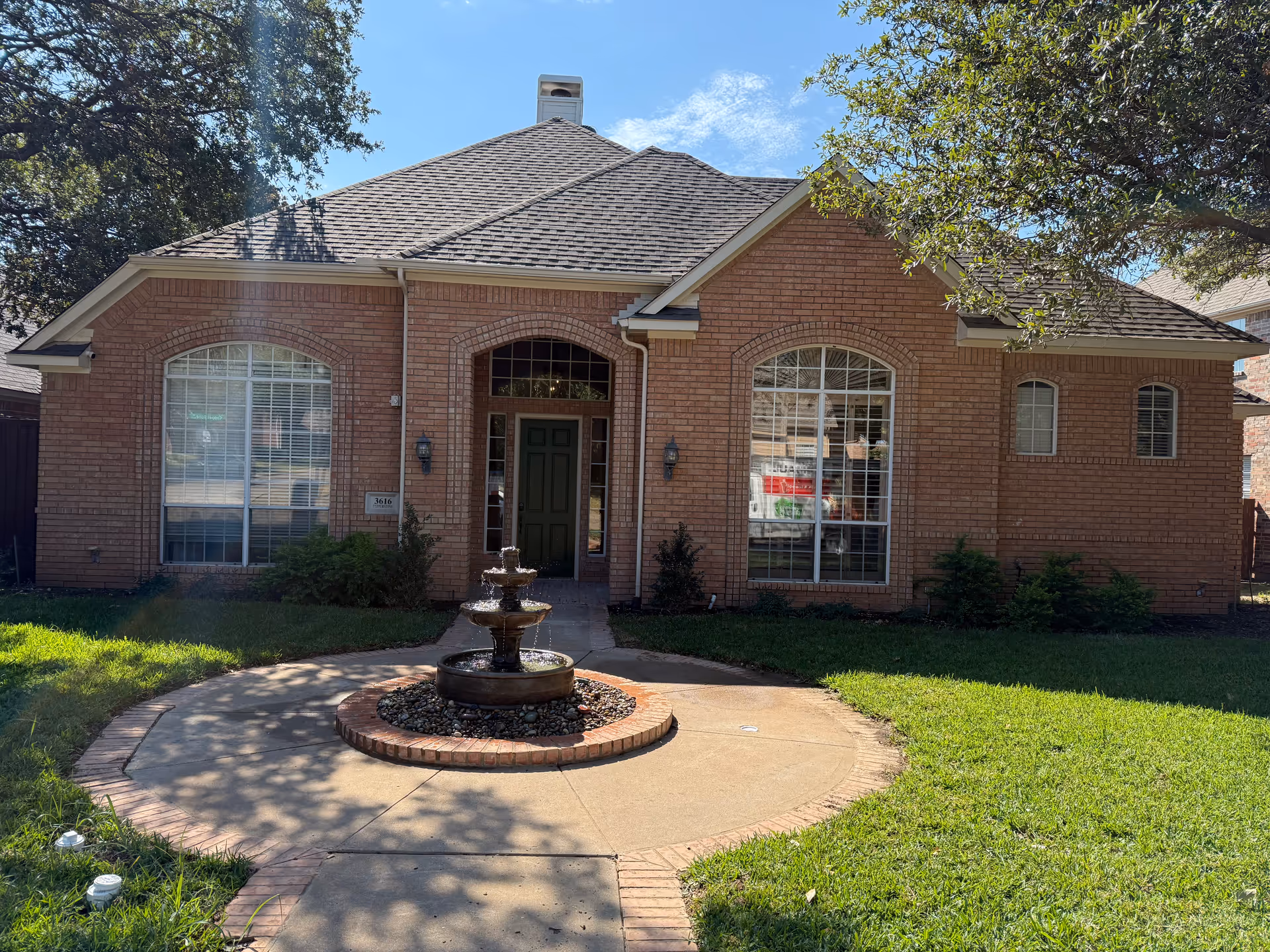 Brick, single-story assisted living facility front with fountain and manicured lawn