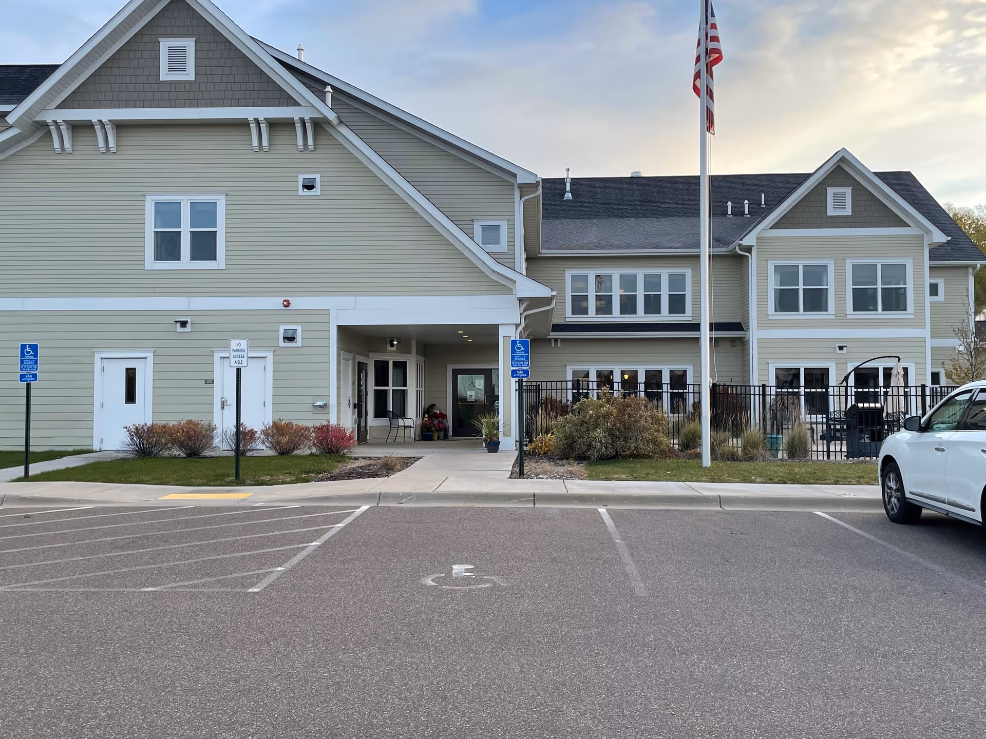 Front view of Volante Senior Living of Hanover, a beige two-story facility with entrance and flagpole.