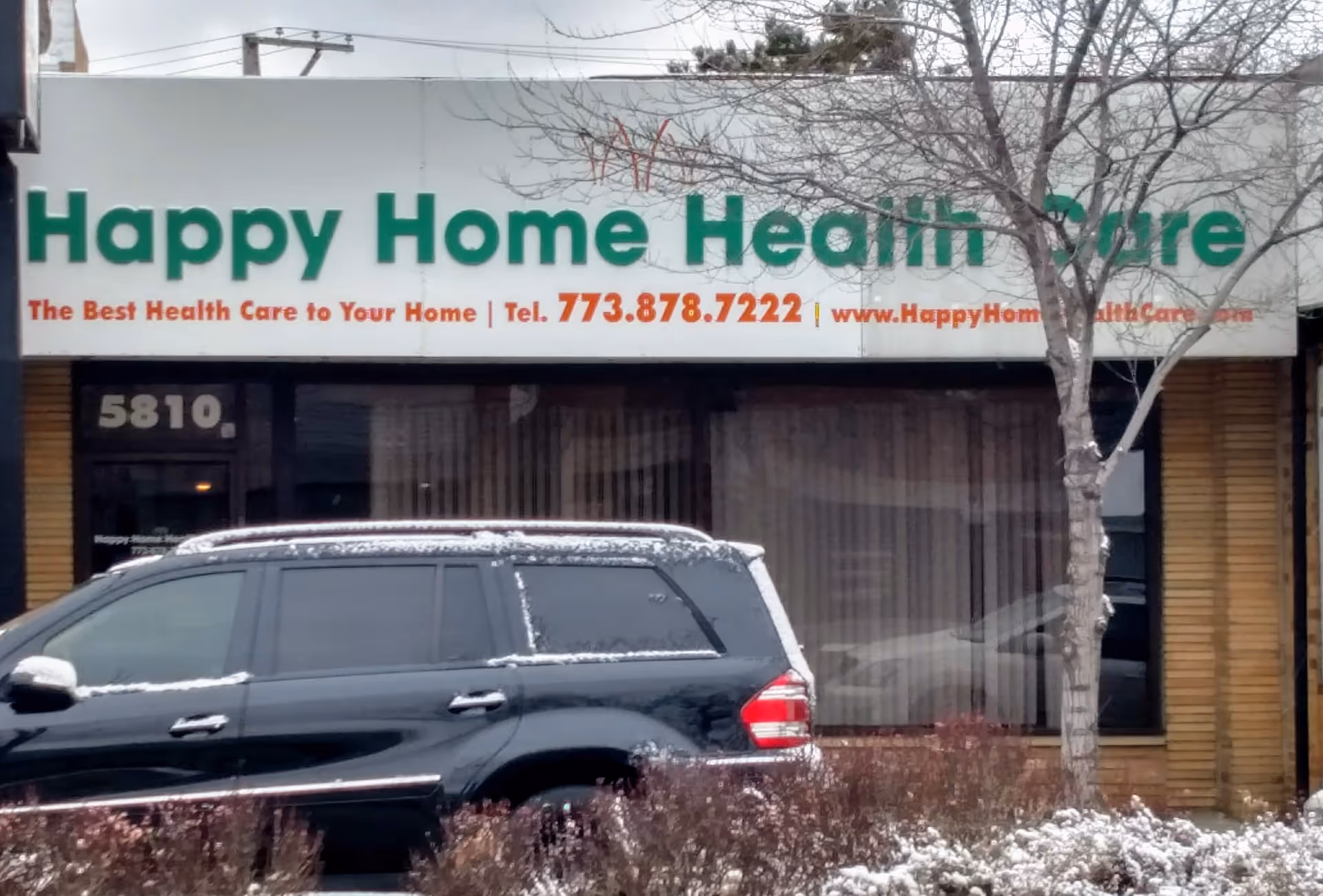 Front view of Happy Home Health Care storefront with a parked car in front.