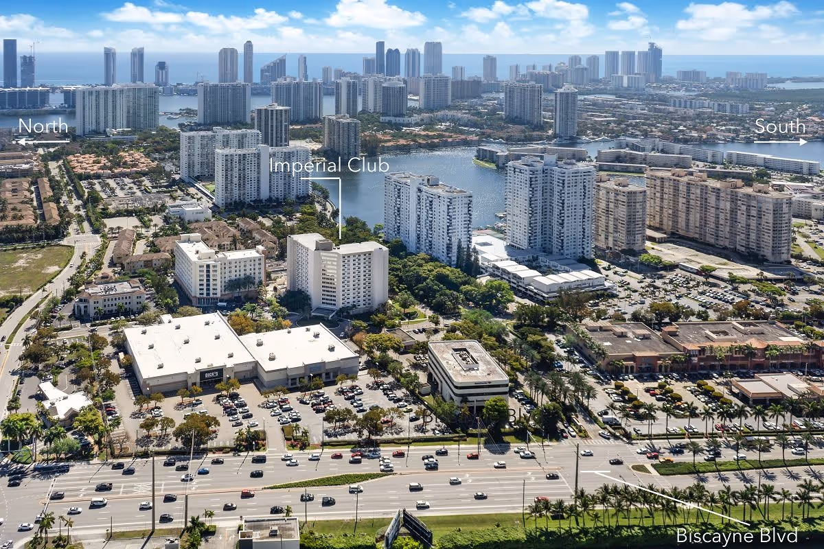 Aerial view of a cityscape showing multiple high-rise buildings, residential complexes, and a water body in the background. The image highlights the location of Imperial Club among other buildings, with labels indicating directions North and South and the nearby Biscayne Blvd road.