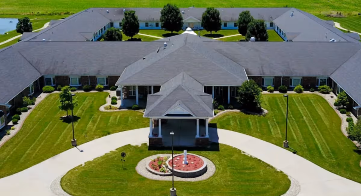 Aerial view of a U-shaped senior living facility with circular driveway and manicured lawn.