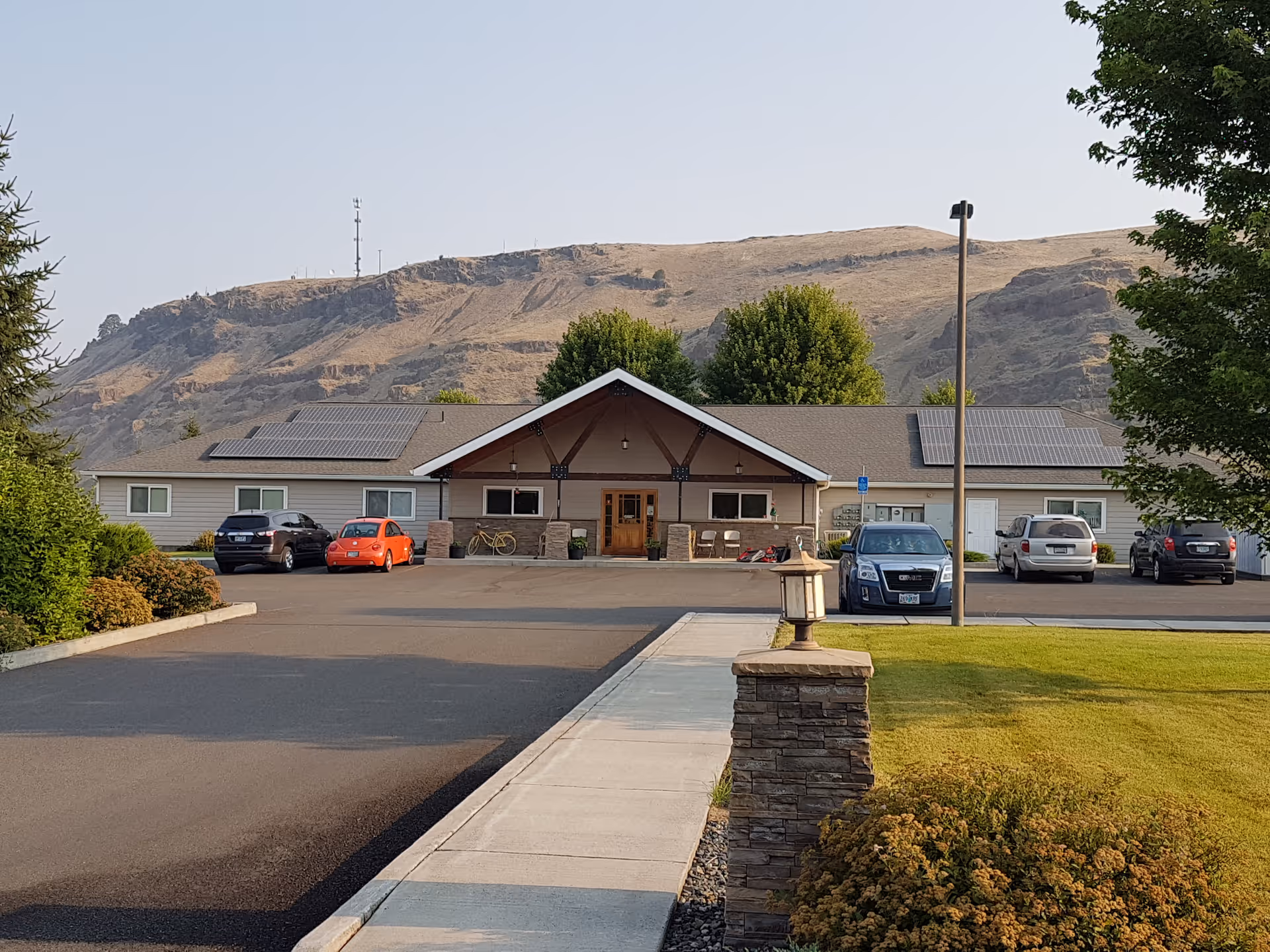 Front view of a single-story senior living facility, parking lot, and distant mountains.