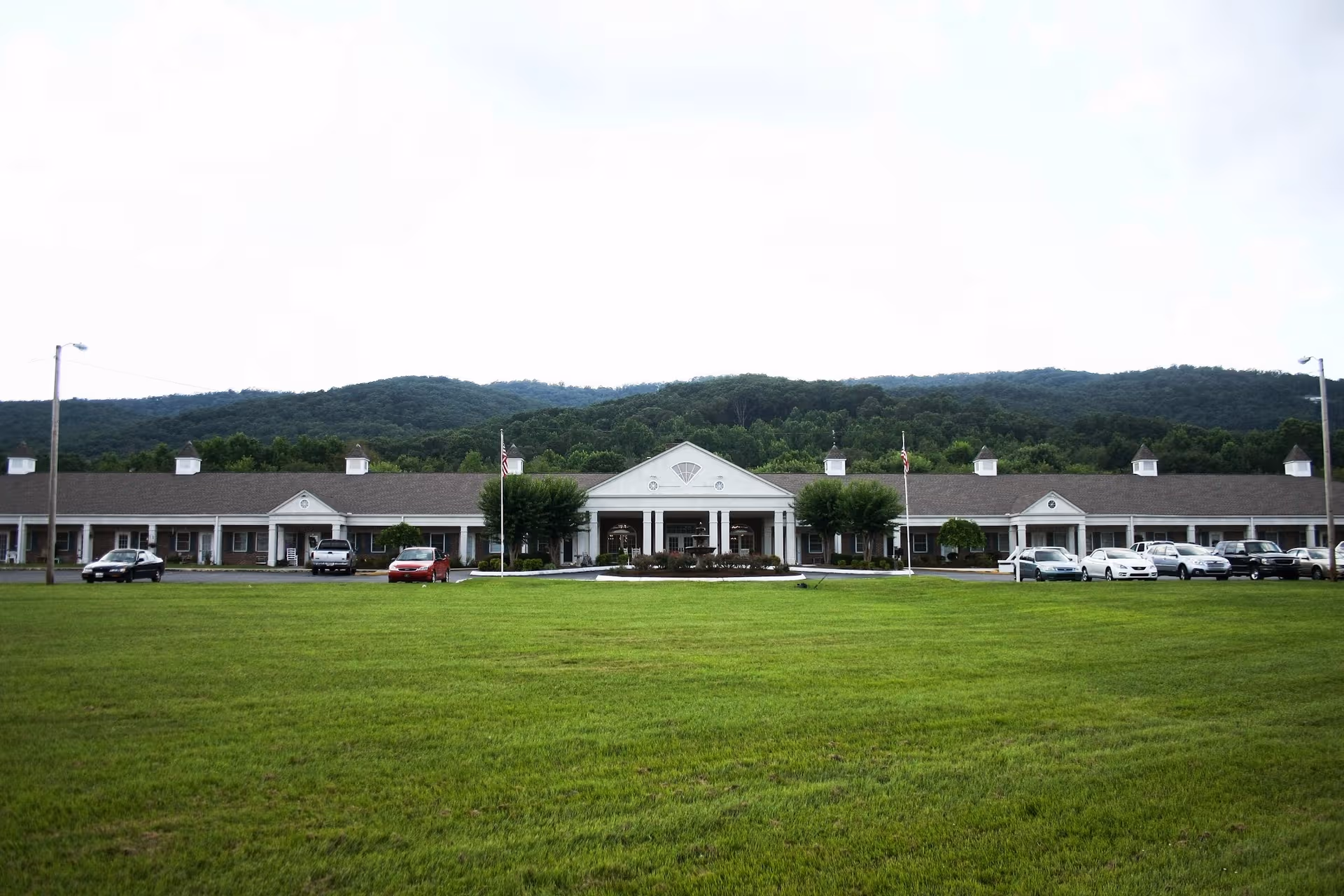 Exterior view of Oaks at Dalton facility with a long central entrance and green lawn.