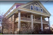 Two-story house-style senior living home with wide porch and decorative columns.