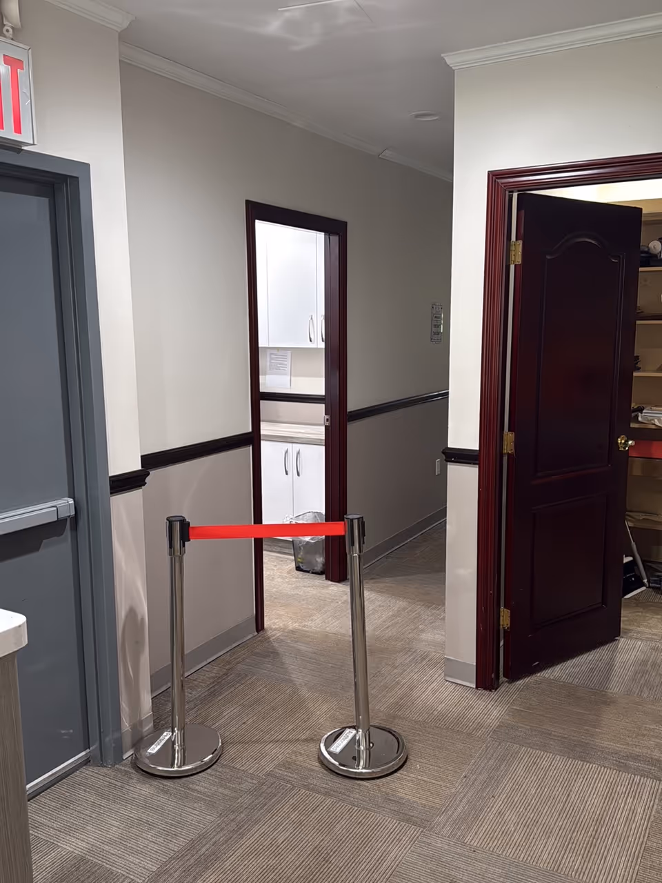 Interior hallway in a senior living facility with stanchions and open doors.