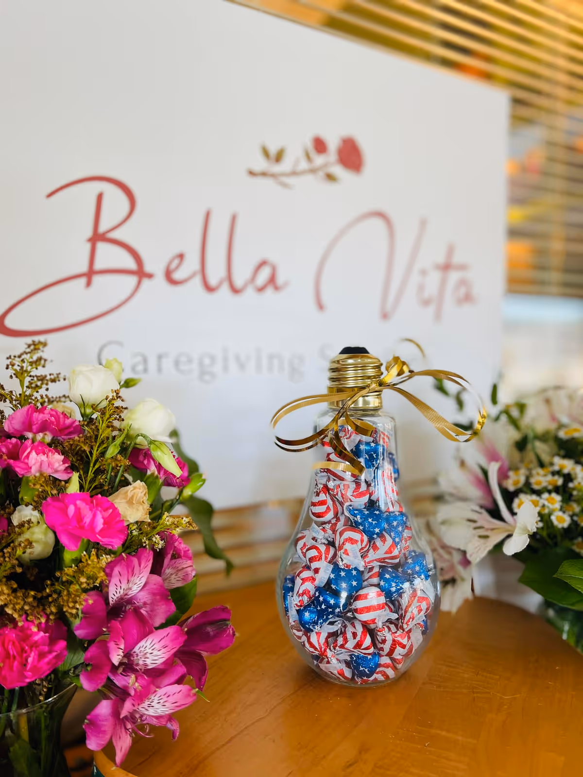 Decorative table display with flowers and a candy-filled bottle; Bella Vita sign visible.