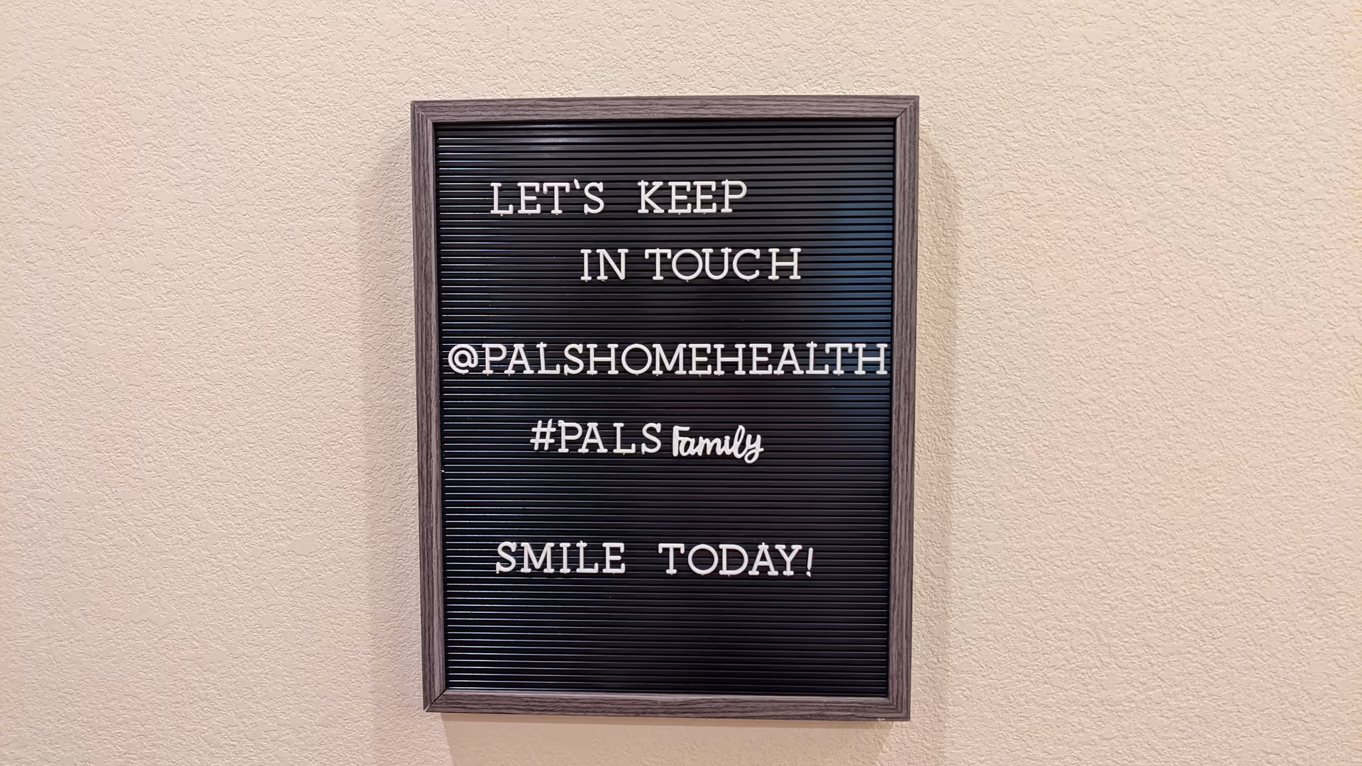 Framed letter board on a beige wall displaying 'Let's keep in touch' message.